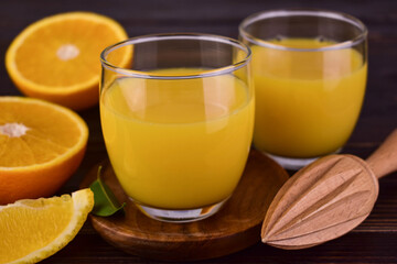 Fresh orange juice with in glasses on a dark wooden background.