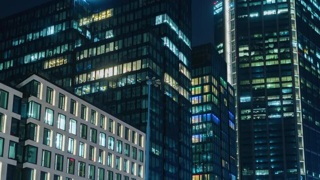 Day to night transition blinking office window lights time-lapse, windows grid, high-rise skyscraper business buildings in downtown, glass surface, turn on and off lights, people working in evening