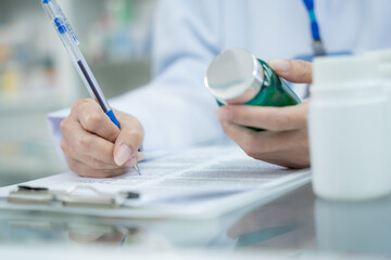 Close up female pharmacist hand writing drug detail in paper. Pharmacy, Medical, Healthcare,...