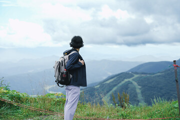 Tourist girl looking out to beautiful mountains view at Hakuba Happo One, Japan.