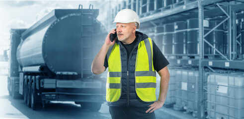 Man is logistician. Fuel transportation specialist. Logistics in oil and gas industry. Man with phone near petrol station. Logistician in helmet makes call. Guy near stacks of fuel barrels