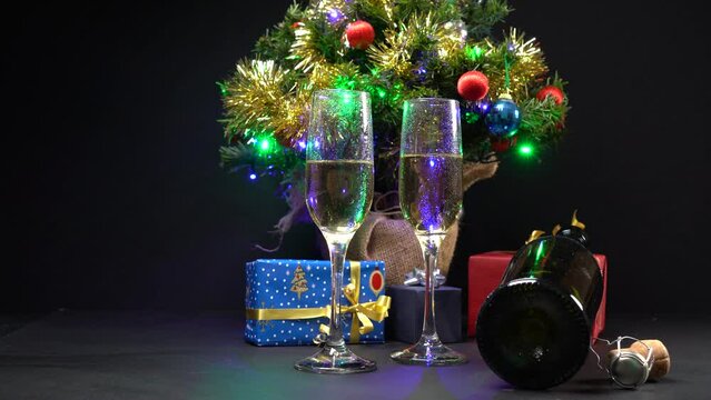 Albero di Natale con luci colorate, pacchetti regalo e bicchieri di champagne