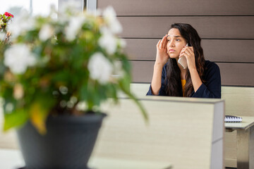 Worried woman looking into infinity while talking on a cell phone sitting in a coffee shop
