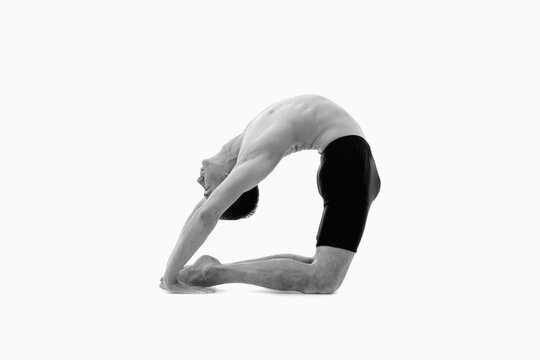 Kapotasana (Pigeon Pose), Ashtanga yoga  Side view of man wearing sportswear doing Yoga exercise against white background. Black and white image.