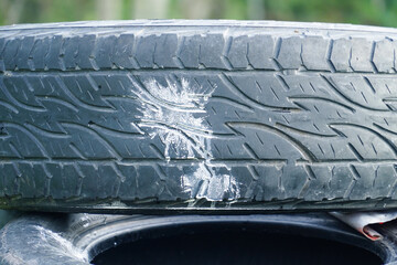 White paint splash from a crashed paintball on an old car tire with a zigzag tread pattern