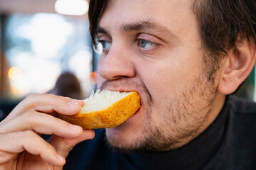 Male man eats fresh white bread. Homemade sourdough bread. Hungry caucasian man portrait close-up, lifestyle