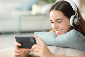 Happy woman wearing headphone watching media