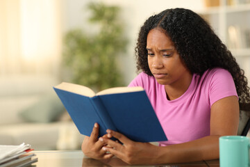 Sad black woman reading a book at home