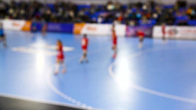 A women's sports team plays indoor handball. Blurry.
