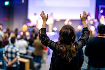 Woman with her hands raised to prayer in the church - obrazy, fototapety, plakaty