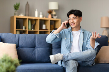 Japanese young man smiling talking on smartphone sitting at home