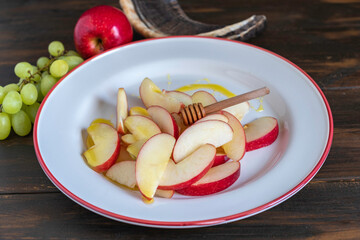 Honey stick on sliced apples in ceramic plate for Jewish holiday Rosh Hashanah.