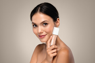 Smiling young caucasian brunette woman hold base foundation cream
