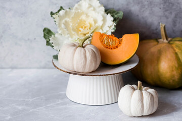 Seasonal autumn food. Fresh pumpkins and decorative cabbage on a background of gray marble.