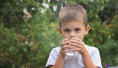 a boy drinks water from a glass in nature. Selective focus