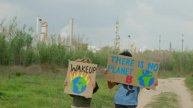 Young activists rally outside a polluting factory, holding signs against pollution, global warming, and advocating for ecological awareness and a hopeful future. Factories emit CO2 and toxic smoke.