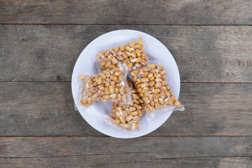 roasted soybeans In Transparent Small Plastic Packaging on a white plate. On wooden Background. nuts in plastic packaging