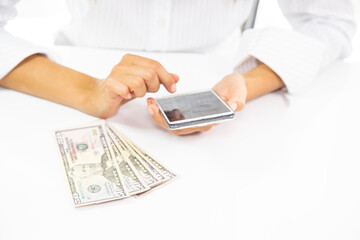 Close-up of woman's hand using calculator and stacks of dollar bills