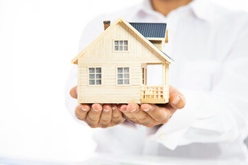 Close-up of woman's hands holding a small model house.