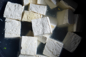 Fresh raw white tofu sell in a traditional market. Buckets of sliced raw tofu or tahu made from...