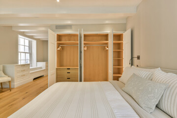 a bedroom with a bed, dresser and mirror in the corner to the other room where there is an open closet