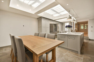 a kitchen and dining area with skylights on the ceiling over the island, which has been used as an...