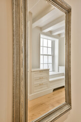 a large mirror in the corner of a room with white walls and hardwood flooring on the other side of the frame