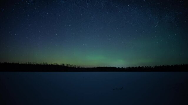 Time lapse of aurora borealis over a frozen lake in forests of Pirkanmaa, Finland