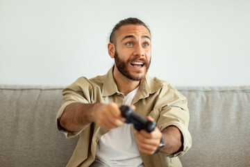 Young emotional man playing video games at home