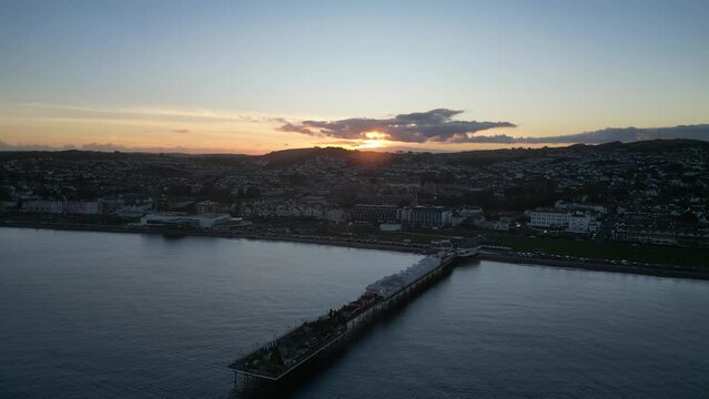 Paignton, Torbay, South Devon, England: DRONE VIEWS: Paignton Pier at sunset. Paignton is a popular UK holiday resort; the Pier was completed in 1879 during the reign of Queen Victoria (Clip 7).