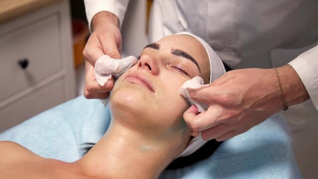 A young woman with clean skin is preparing for a cosmetic procedure. Cleansing the face of a young beautiful lady lying in a cosmetology room.