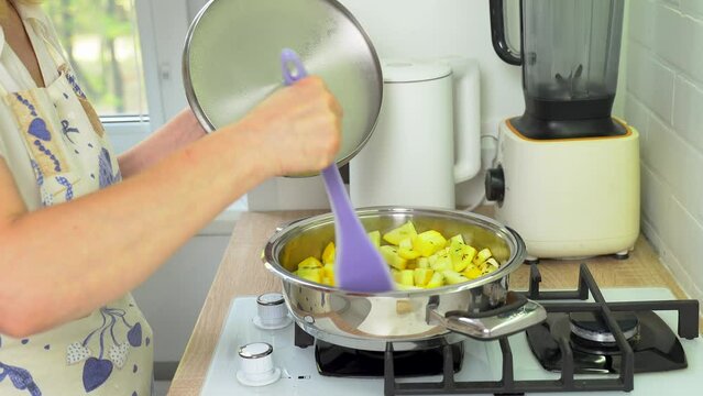 Stir diced zucchini in a frying pan. Cooking food.