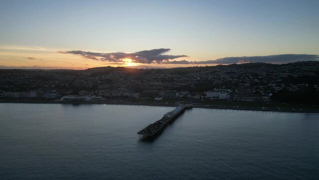Paignton, Torbay, South Devon, England: DRONE VIEWS: Paignton Pier at sunset. Paignton is a popular UK holiday resort; the Pier was completed in 1879 during the reign of Queen Victoria (Clip 3).