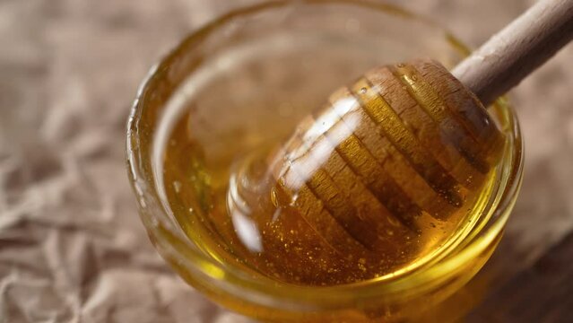 Healthy organic thick honey, dipped with a wooden spoon for honey, close-up macro. Slow motion