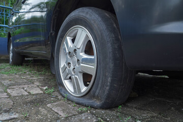 flat car tire in the parking lot, textured with bricks. seems to have been abandoned