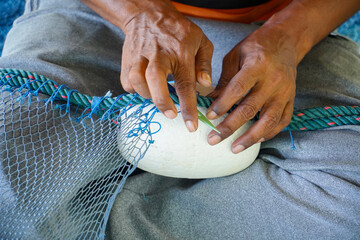 Close up View of Fisherman Fixing Fishing Net, knitting a trawl net, traditional way