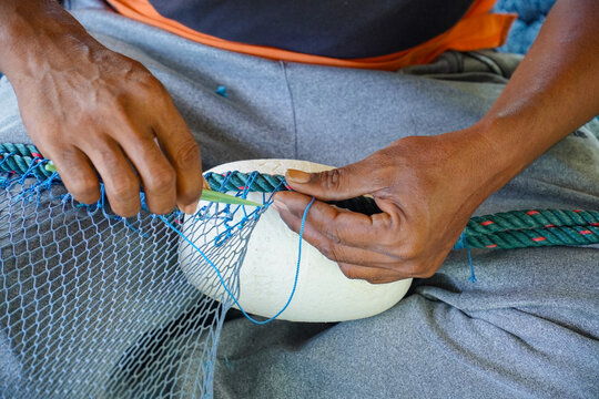 Close up View of Fisherman Fixing Fishing Net, knitting a trawl net, traditional way