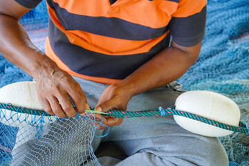 Close up View of Fisherman Fixing Fishing Net, knitting a trawl net, traditional way