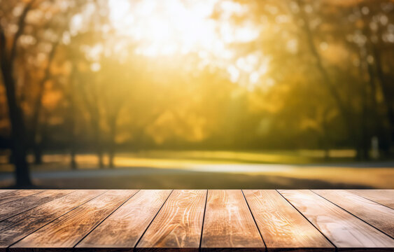 Wooden table top on blurred background of trees in the park with sunshine light. High quality photo