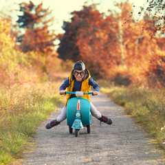 Spaß im Herbst, kleiner Junge fährt Moped