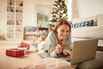 Young woman online shopping on a laptop for presents during the Christmas holidays at home