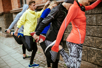 Young and diverse group of friends stretching and getting ready to exercise and run in the city