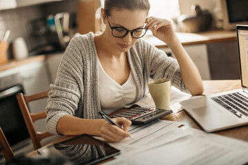 Young woman doing financials in the kitchen