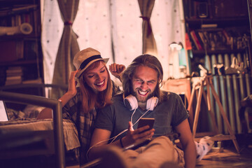 Young couple using the smartphone together on the floor of their apartment