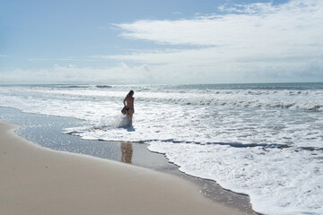 A Caucasian woman walking on the sands of a tropical beach in northeastern Brazil.