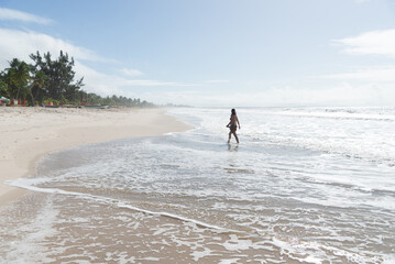 A Caucasian woman walking on the sands of a tropical beach in northeastern Brazil.