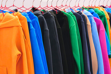 Fashion hoodie clothes on clothing rack  Closeup of rainbow color choice female wear on hangers in a clothing store closet  Summer home wardrobe.