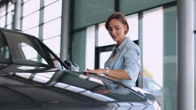 Business woman in car showroom choosing a new car