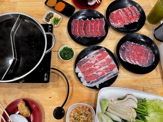 Chinese spicy hotpot soup. Plates of raw meat slides and vegetable at restaurant.