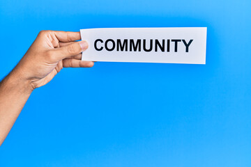 Hand of caucasian man holding paper with community word over isolated white background